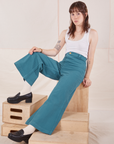 Hana is sitting on a wooden crate wearing Petite Bell Bottoms in Marine Blue and Cropped Tank Top in vintage tee off-white