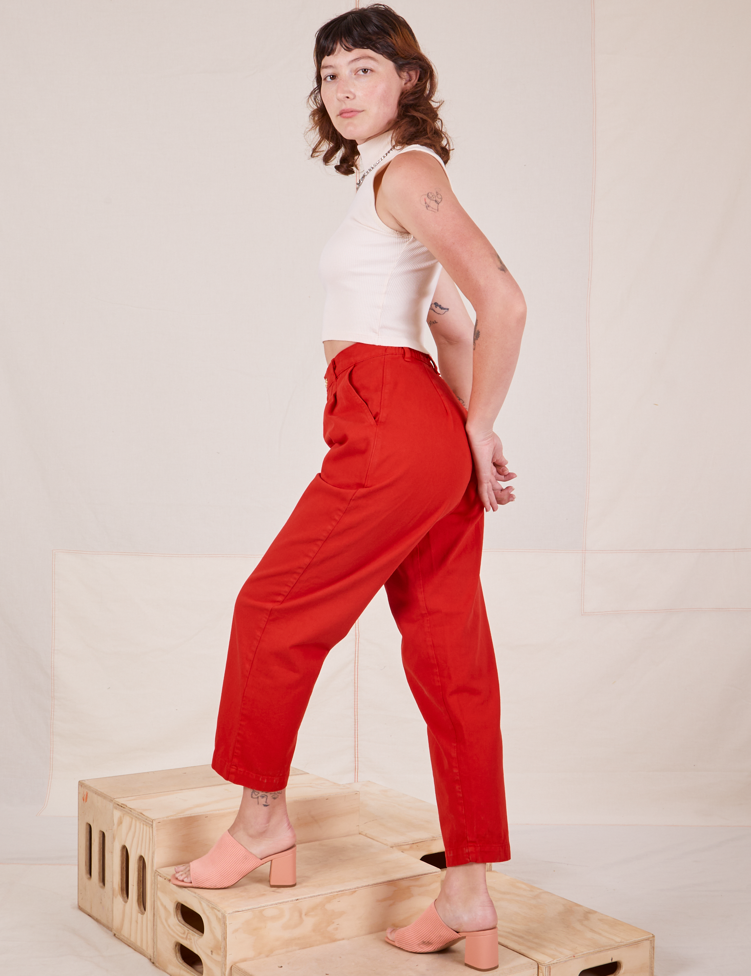 Angled side view of Heavyweight Trousers in Mustang Red and Sleeveless Turtleneck in vintage tee off-white worn by Alex