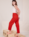 Angled side view of Heavyweight Trousers in Mustang Red and vintage off-white Sleeveless Turtleneck worn by Alex