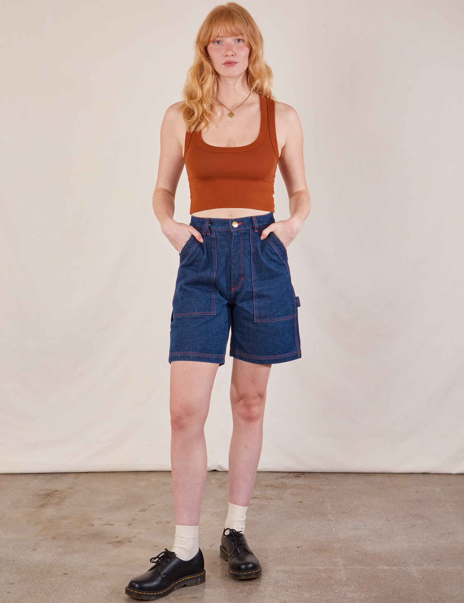 Margaret is 5'11" and wearing XS  Carpenter Shorts in Dark Wash paired with burnt terracotta Cropped Tank