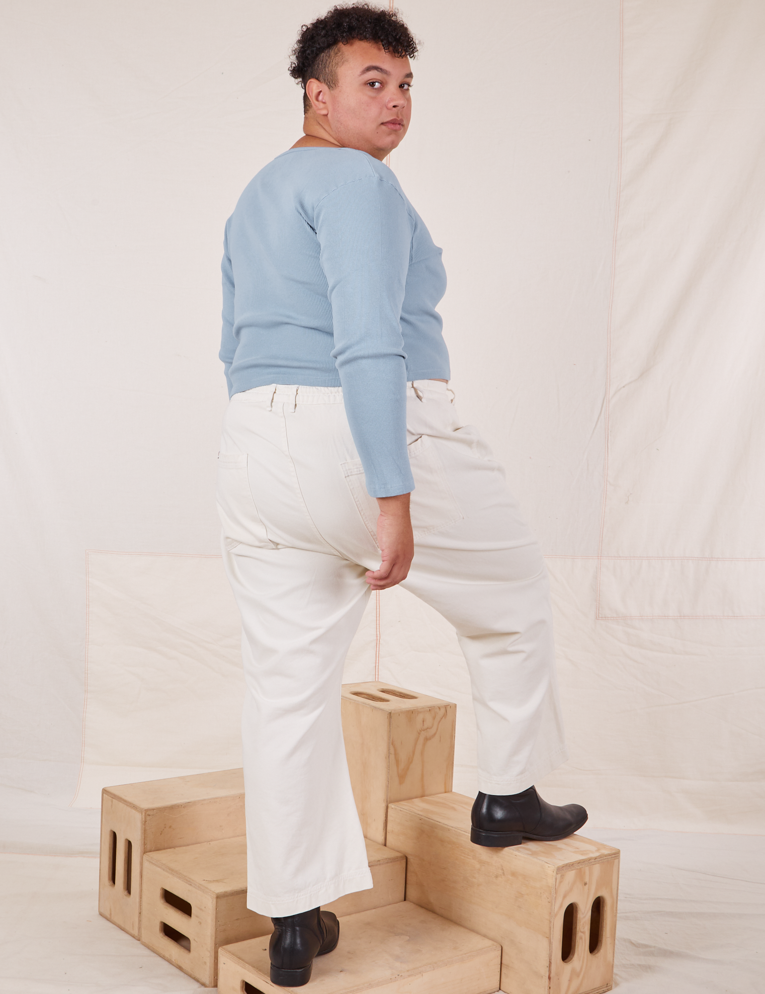 Angled back view of Long Sleeve V-Neck Tee in Periwinkle and vintage tee off-white Western Pants on Miguel
