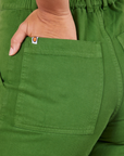 Back pocket close up of Short Sleeve Jumpsuit in Lawn Green. Gabi has her hand in the pocket.