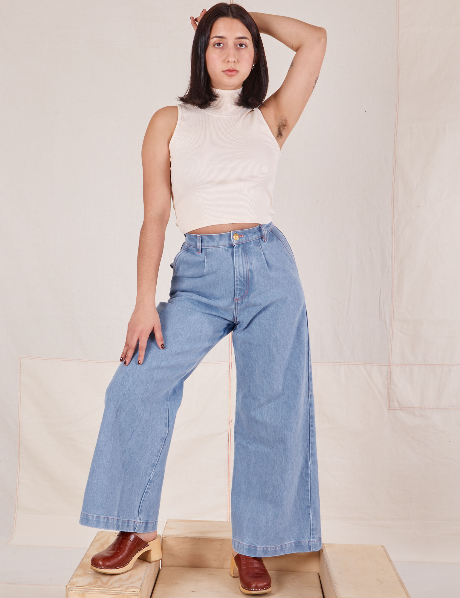 Betty is 5&#39;8&quot; and wearing XXS Indigo Wide Leg Trousers in Light Wash paired with vintage off-white Sleeveless Turtleneck