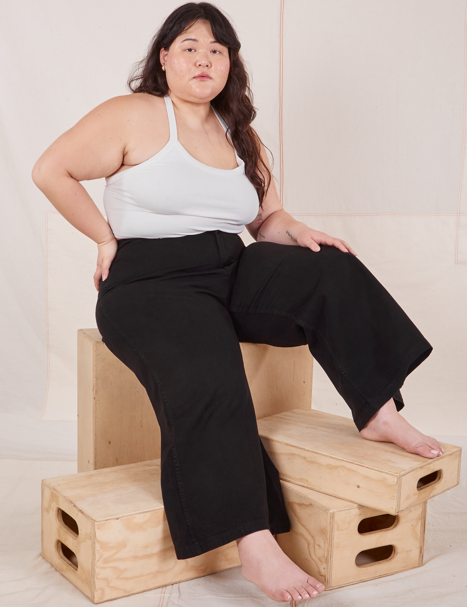 Ashley is wearing Petite Bell Bottoms in Basic Black and Halter Top in vintage tee off-white