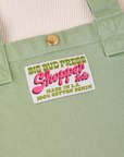 Sun Baby brass snap on Shopper Tote Bag in Sage Green. Bag label with green and pink text that reads "Big Bud Press Shopper Tote, Made in L.A., 100% Cotton Denim" on white background