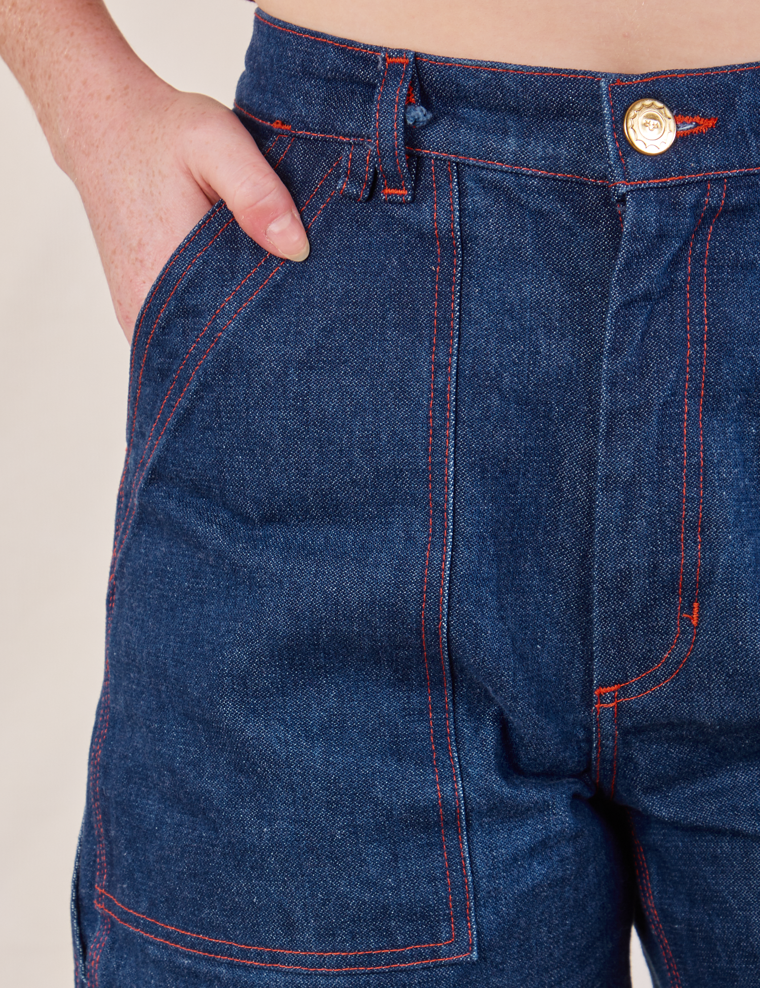 Carpenter Shorts in Dark Wash front pocket close up. Margaret has her hand in the pocket.