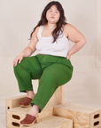 Ashley is sitting on a wooden crate wearing Heavyweight Trousers in Lawn Green and Cropped Tank Top in vintage tee  off-white