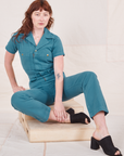 Heritage Short Sleeve Jumpsuit in Marine Blue on Alex sitting on a wooden crate