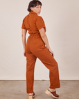 Angled back view of Short Sleeve Jumpsuit in Burnt Terracotta worn by Tiara