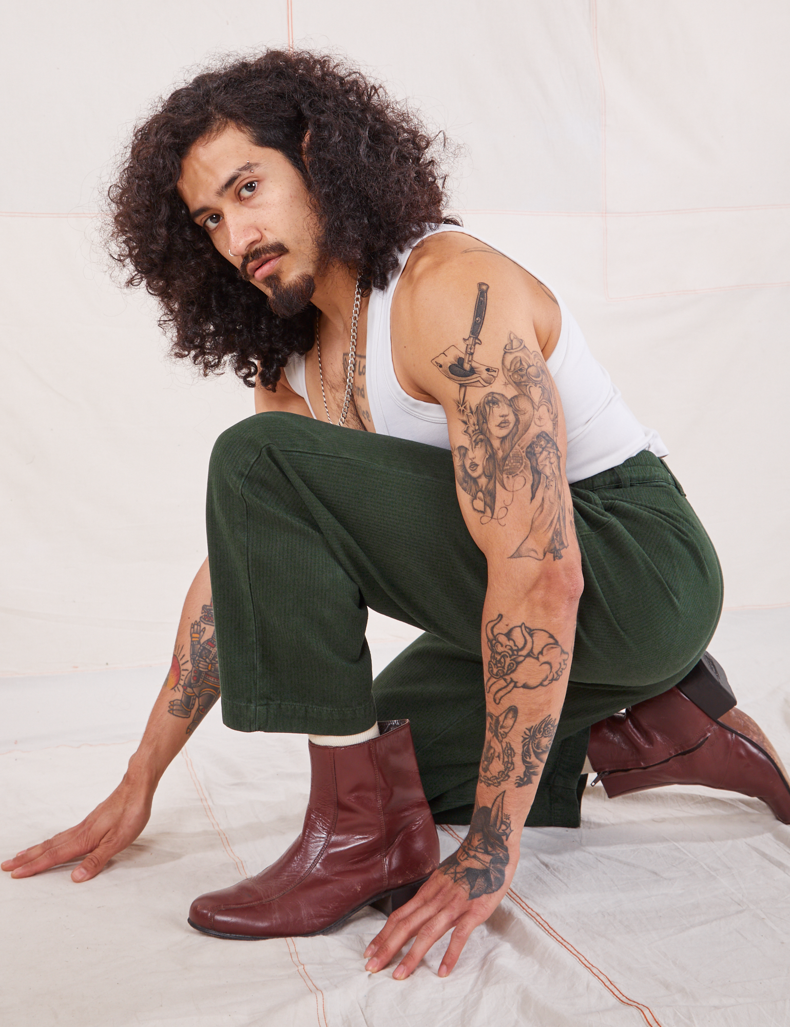 Jesse is wearing Heritage Trousers in Swamp Green and Cropped Tank Top in vintage in off-white
