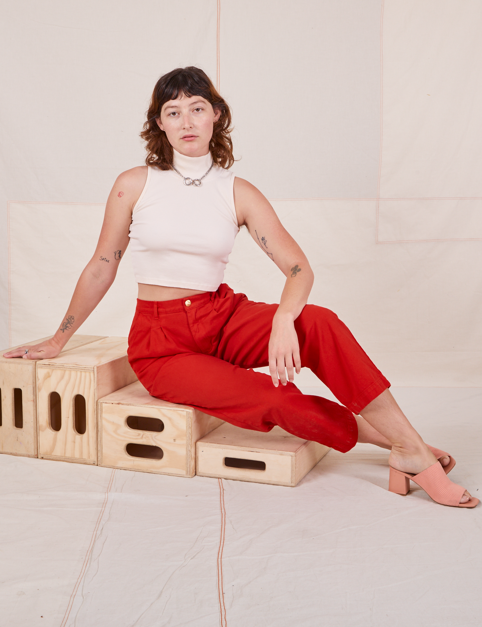 Alex is wearing Heavyweight Trousers in Mustang Red and Sleeveless Turtleneck in vintage tee off-white