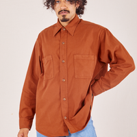 Jesse is wearing a buttoned up Oversize Overshirt in Burnt Terracotta