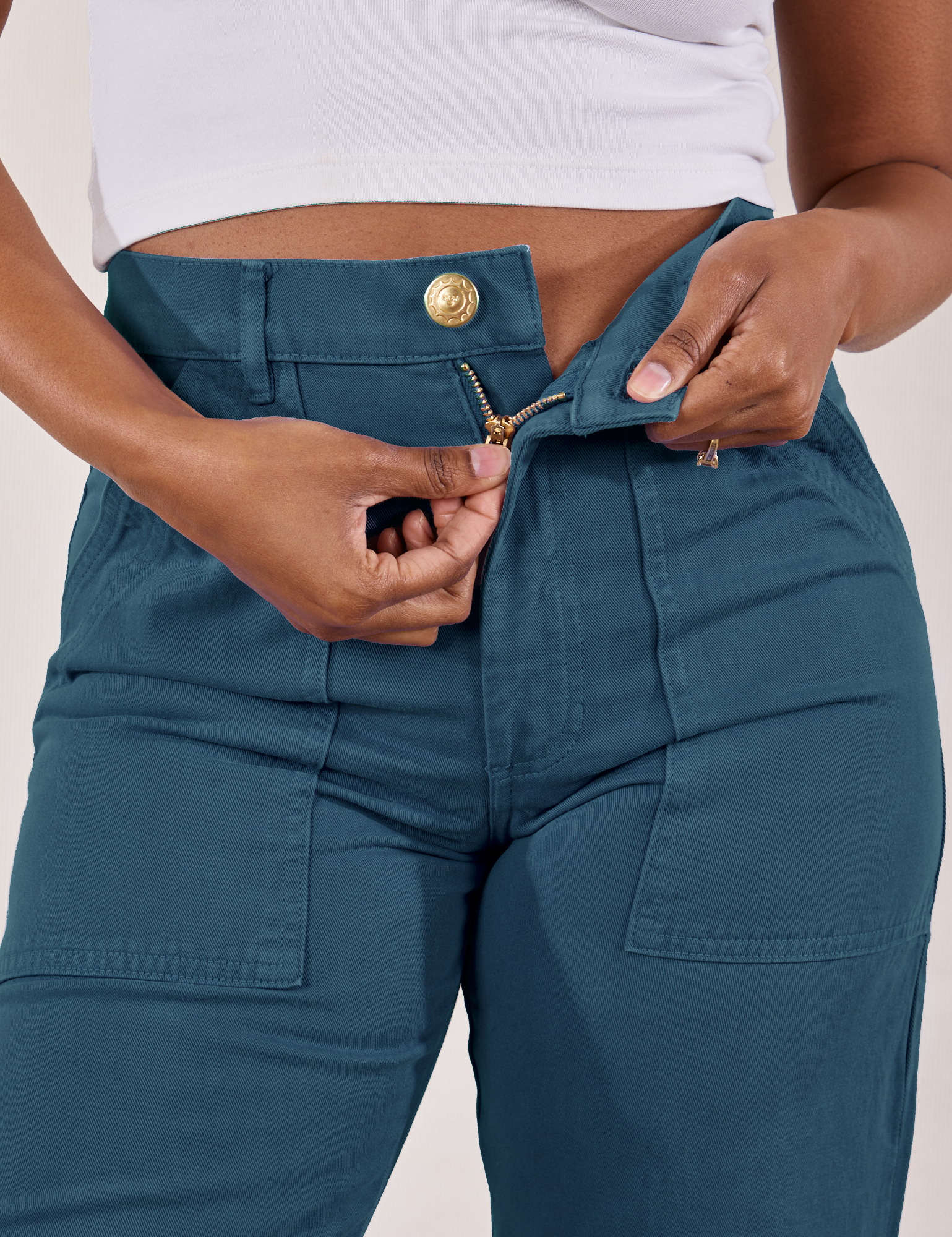 Petite Work Pants in Lagoon front close up. Kandia is pulling down on the zipper tab