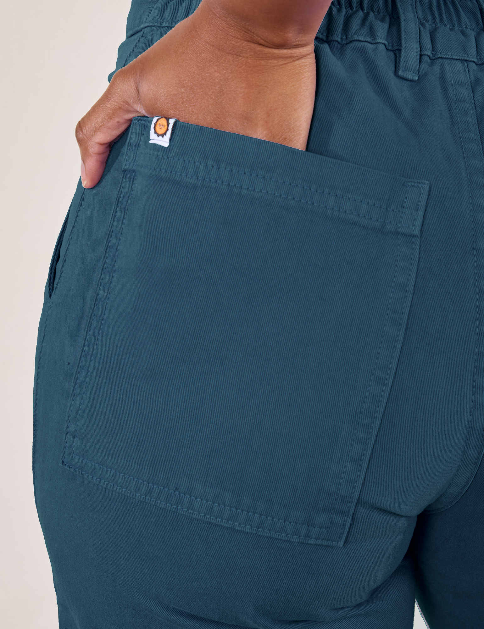 Petite Work Pants in Lagoon back pocket close up. Kandia has her hand in the back pocket.