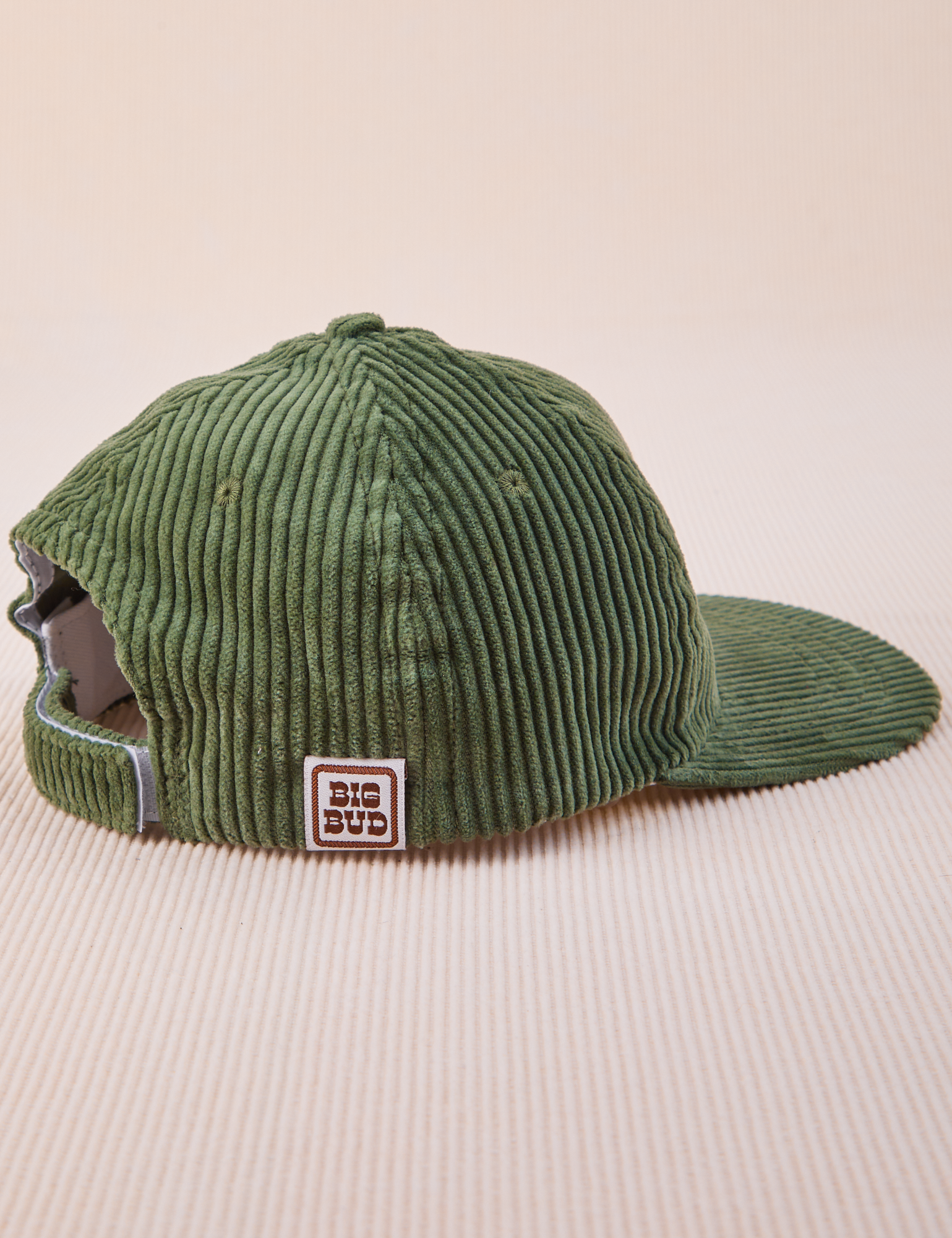 Side view of Dugout Corduroy Hat in Emerald Green. Big Bud label sewn on edge of hat.