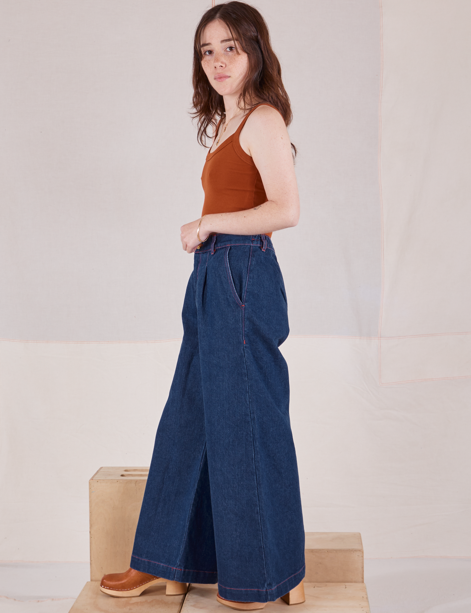 Side view of Indigo Wide Leg Trousers in Dark Wash and burnt terracotta Cropped Cami on Hana