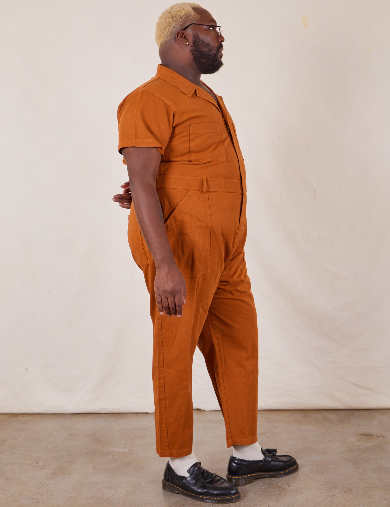 Side view of Short Sleeve Jumpsuit in Burnt Terracotta worn by Elijah
