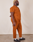 Side view of Short Sleeve Jumpsuit in Burnt Terracotta worn by Elijah