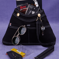 Overall Handbag in Black with book and two cassette tapes in main compartment. Keys hanging from brass hardware in the front. Sunglasses in the front pocket.
