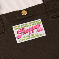 Sun Baby brass snap on Shopper Tote Bag in Espresso Brown. Bag label with green and pink text that reads "Big Bud Press Shopper Tote, Made in L.A.,100% Cotton Denim" on white background