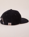 Side view of Dugout Corduroy Hat in Black. Big Bud label sewn on edge of hat.