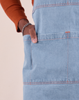 Isaac has his hand in the front pocket of the Full Indigo Denim Apron in light wash