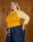 Side angled view of Juliet wearing the Mustard Yellow/Butter Raglan Tee