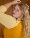 Angled back view close up of Juliet in the Mustard Yellow/Butter Raglan Tee