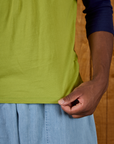 Close up of the hem of the Gross Green/Navy Colorblock Raglan Tee on Isaac