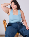 Ashley is sitting in a chair wearing Cropped Tank Top in Baby Blue and dark wash Indigo Wide Leg Trousers