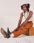 Jerrod is wearing Heavyweight Trousers in Burnt Terracotta and Sleeveless Turtleneck in vintage tee off-white