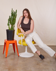 Allison is sitting in a yellow and white chair wearing Work Pants in Vintage Tee Off-White and an espresso brown Tank Top
