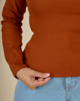 Close up of the hem on the Burnt Terracotta Long Sleeve Baby Tee worn by Tiara