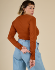 Angled back view of Tiara in the Burnt Terracotta Long Sleeve Baby Tee
