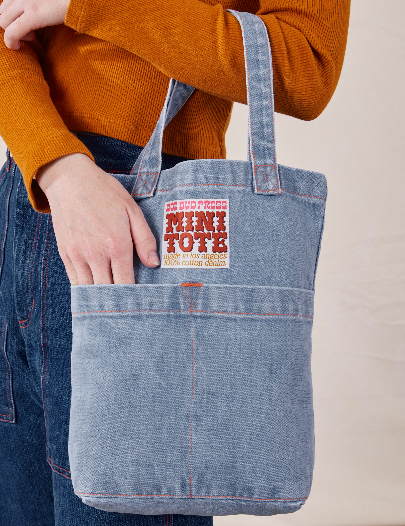 Denim Mini Tote Bag in Light Wash on model&#39;s arm with her hand in the front pocket