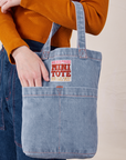 Denim Mini Tote Bag in Light Wash on model's arm with her hand in the front pocket