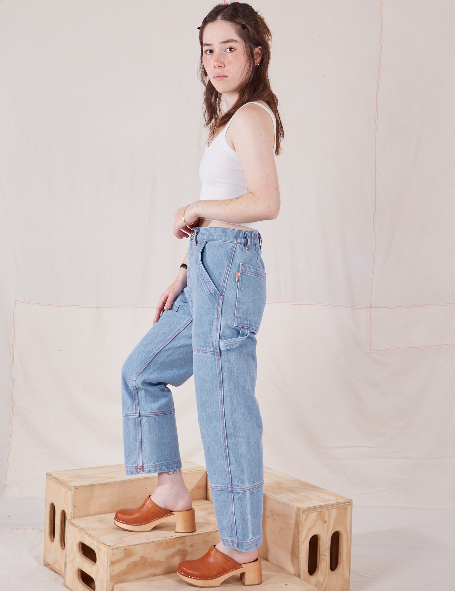 Side view of Petite Carpenter Jeans in Light Wash and vintage off-white Cami on Hana