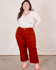 Ashley is 5'7 and wearing 1XL Petite Western Pants in Paprika paired with a Long Sleeve V-Neck Tee in vintage tee off-white 