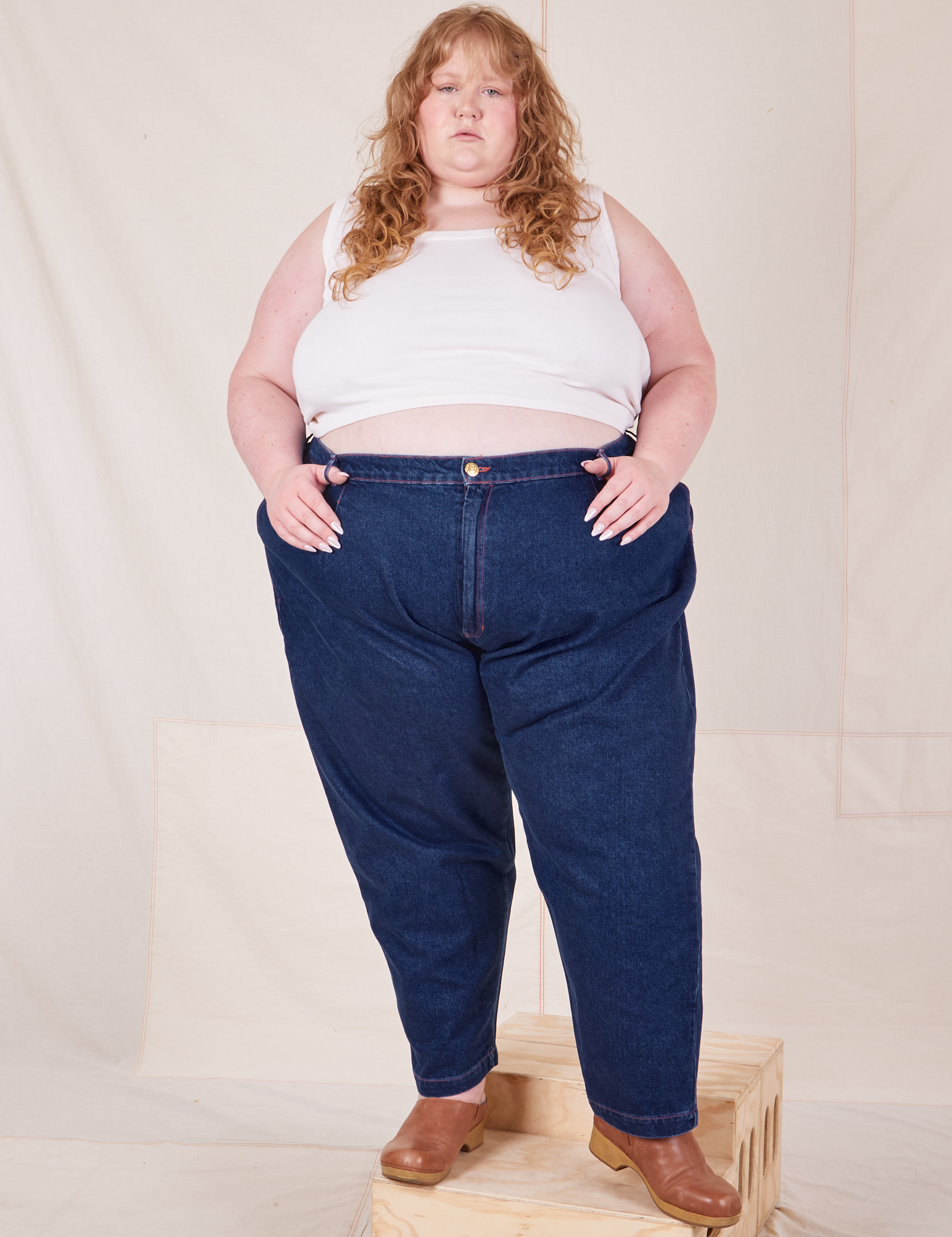 Catie is 5&#39;11&quot; and wearing 4XL Denim Trouser Jeans in Dark Wash paired with a Tank Top in vintage tee off-white