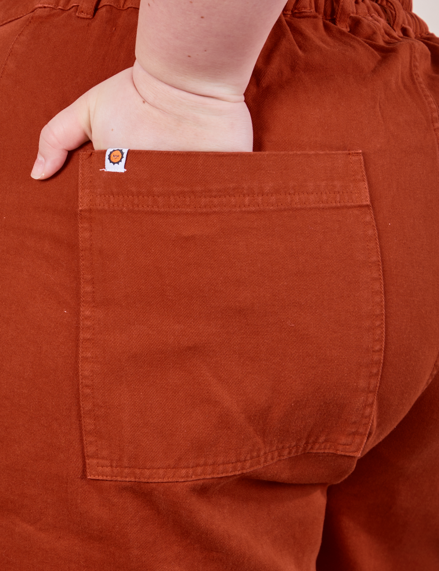 Classic Work Shorts in Paprika back pocket close up. Ashley has her hand in the pocket.