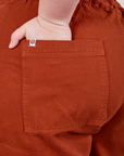 Classic Work Shorts in Paprika back pocket close up. Ashley has her hand in the pocket.