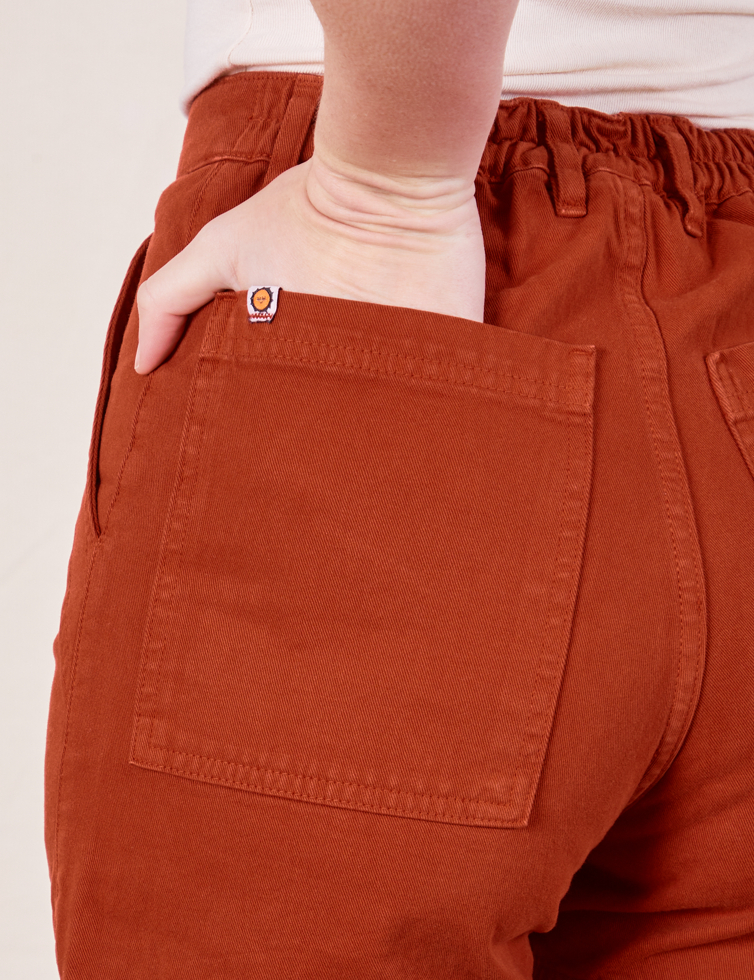 Classic Work Shorts in Paprika back pocket close up. Alex has her hand in the pocket.