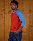 Angled side view of Isaac wearing the Mustang Red/Blue Colorblock Raglan Tee