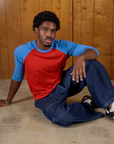 Isaac wearing the Mustang Red/Blue Colorblock Raglan Tee with Dark Wash Denim Drop Pocket Pants