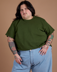 Sam is wearing Burly Tee in Evergreen tucked into light wash Indigo Wide Leg Trousers