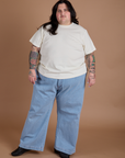 Sam is wearing Burly Tee in Vintage Tee White and light wash Indigo Wide Leg Trousers