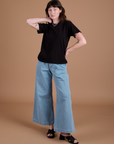 Alex is 5'8" and wearing P Burly Tee in Basic Black paired with light wash Indigo Wide Leg Trousers