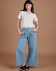 Alex is wearing Burly Tee in Vintage Tee White and light wash Indigo Wide Leg Trousers