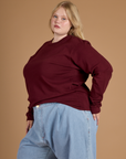 Juliet wearing the Red Wine Long Sleeve Burly Tee tucked into the Light Wash Wide Leg Denim Trousers