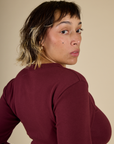 Close up angled back view of Mika wearing the Red wine Long Sleeve Baby Tee
